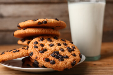 Plate of tasty cookies with chocolate chips on wooden background, closeup