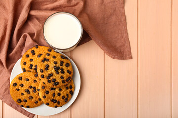 Glass of fresh milk and tasty cookies with chocolate chips on wooden background