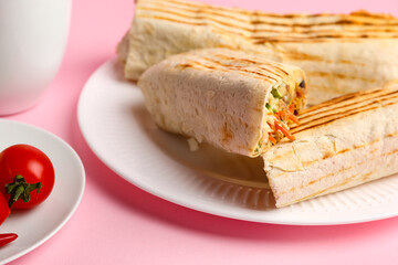 Plates with tasty shawarma and tomatoes on pink background