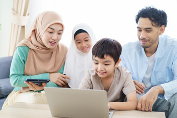 Cheerful - happy Asian muslim family relaxing together in living room.