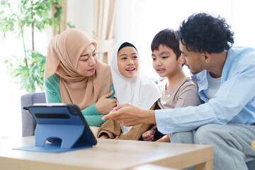 Fototapeta premium Cheerful - happy Asian muslim family relaxing together in living room.