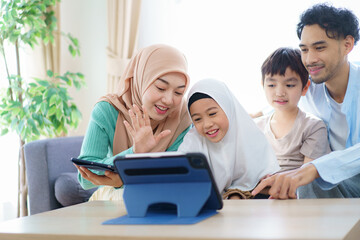 Cheerful - happy Asian muslim family relaxing together in living room.
