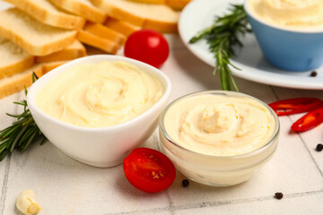 Bowls of tasty cream cheese on white tile background