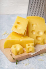 Board with pieces of Swiss cheese on white table
