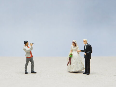 Mini toy of action figure at outdoor with blurred background. Business photography concept design. Minifigure of couple man and woman character with photographer. Wedding photo.