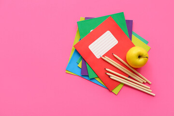 Obraz na płótnie Canvas Colorful notebooks with fresh apple and pencils on pink background