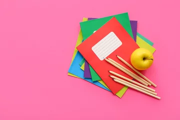 Fotobehang Colorful notebooks with fresh apple and pencils on pink background © Pixel-Shot