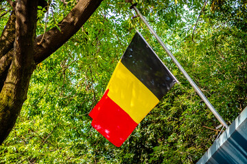 Belgian flag waving with green trees in the background, at the Belgian Embassy in Mexico City 