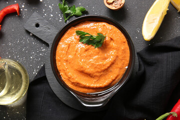 Bowl of tasty muhammara on black background