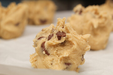 Close up of balls of uncooked chocolate chip cookie dough.