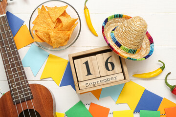 Cube calendar with date SEPTEMBER 16, nachos, chilli peppers and sombrero on white wooden...