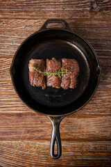 Seared Steak in Cast Iron Skillet on Rustic Wooden Surface