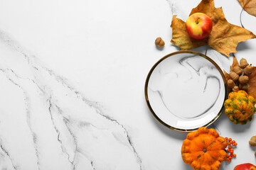 Autumn table setting with pumpkins, chestnuts and dried leaves on white background