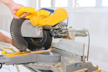 Contractor carefully uses miter saw to cut wood in well lit workshop, on accuracy craftsmanship.