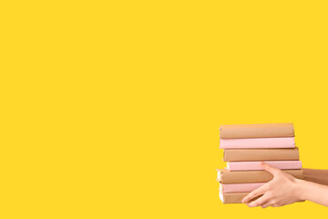 Hands holding books on yellow background