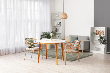 Stylish interior of spacious living room with table, armchairs, sofa, houseplants and shelving unit