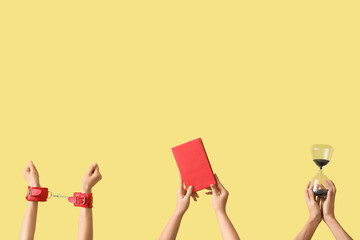 Female hands holding hourglass, handcuffs and book on yellow background