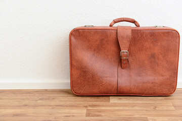 Brown retro leather suitcase on floor in room