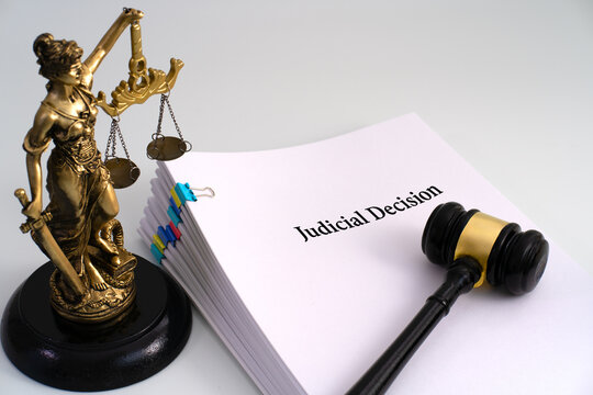 A Lady Justice statue beside a stack of documents titled 'Judicial Decision,' with a gavel resting on top, symbolizing the authority and finality of a legal ruling