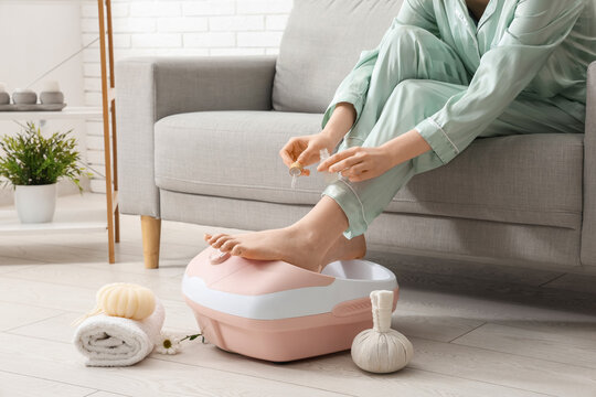 Woman with massage foot bath, essential oil and spa accessories at home