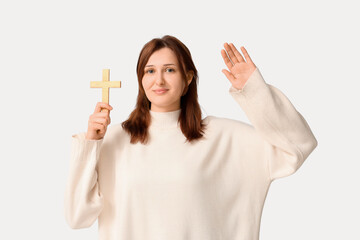 Religious young woman with wooden cross raising hand on white background