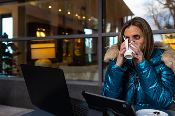 Businesswoman drinking coffee while working on laptop at outdoor cafe