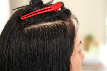 Young woman getting hair extensions in beauty salon, closeup