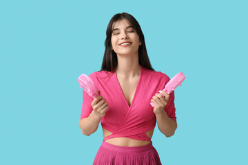 Young woman with mini fans on blue background
