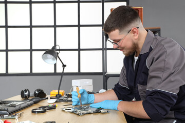 Male technician repairing PC board in service center