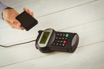 Contactless payment is happening on wooden countertop in flat design, with smartphone and terminal
