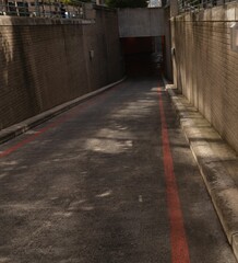 Sloping asphalt ramp is descending into underpass in flat design, with red lines and metal railings