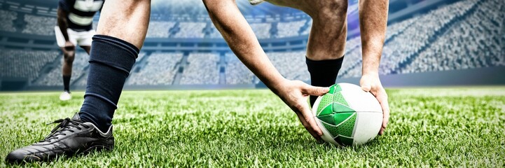 Rugby player picking up the ball in sports stadium