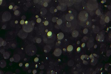 Defocused bokeh lights in various sizes and colors on a dark background creating a dreamy and abstract visual effect