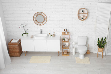 Interior of restroom with toilet bowl shelving unit and chest of drawers with sink
