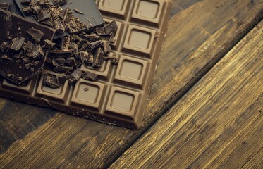 Flat vector milk chocolate bar is resting on weathered plank, revealing dark shards and shavings