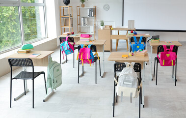Interior of light classroom with projector screen and desks