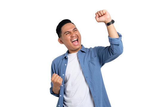 Big win. Excited young Asian man in casual shirt celebrating success with raised fist isolated on transparent background