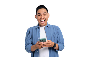 Surprised young Asian man in casual shirt holding smartphone, getting good news, looking at camera...