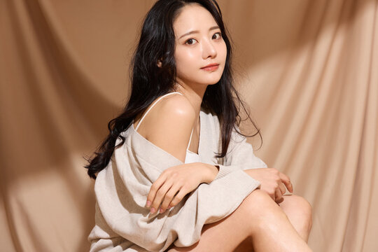 ベージュの布地背景で撮影をした若い女性の高級感のある美容ポートレート