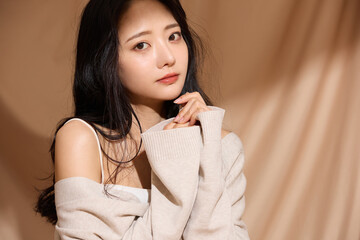 ベージュの布地背景で撮影をした若い女性の高級感のある美容ポートレート