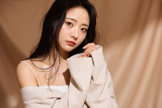 ベージュの布地背景で撮影をした若い女性の高級感のある美容ポートレート