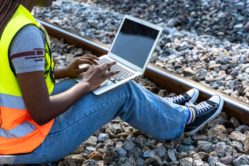 Unknown locomotive engineer sitting and working on laptop maintenance rail track outdoor workplace