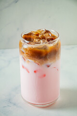 A colorful iced beverage combines pink and brown layers, showcasing creativity and flavor