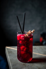 A vibrant drink filled with fresh berries and garnished, set against a dark background