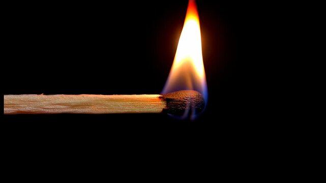 Match ignites with a small flame in a dark environment showcasing the moment of fire starting