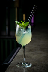 A vibrant cocktail with mint leaves rests atop a marble bar, inviting relaxation and enjoyment