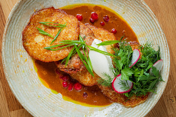 A delicious plate of crispy potato pancakes topped with fresh herbs and a rich, tangy sauce