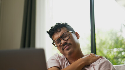 Asian man suffering neck pain after long hours of work.