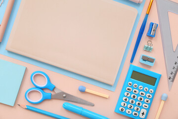 School supplies with notebook, scissors and calculator on beige background. Top view