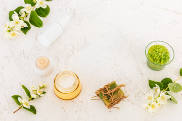 Body care products and branches of jasmine on the white background.